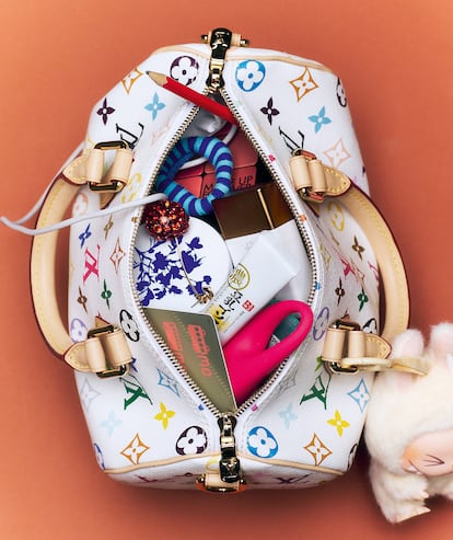 Bolso Speedy de Louis Vuitton Murakami de LOUIS VUITTON; paleta para el rostro de MAKE UP FOREVER; coletero de rayas y pendiente de cereza, ambos de ZARA; gotas bronceadoras D-Bronzi de DRUNK ELEPHANT; bálsamo Botanical Barrier Rescue de THE OUTSET y masajeador para el contorno de ojos de FOREO.