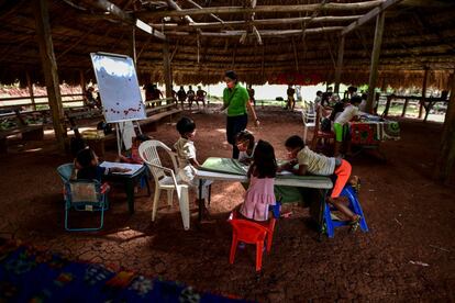 Bouche da una lección a un grupo de niños indígenas en una instalación de palma y con sillas de plástico.