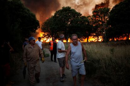 Varias personas abandonan la zona ante la amenaza del fuego, el miércoles.