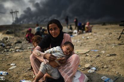 Una madre con dos niños pequeños espera cerca de Qayyarah, tras tener que dejar su hogar a causa del conflicto armado en Mosul.