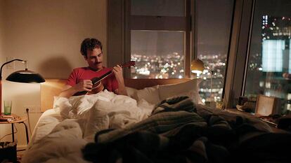Joaquin Phoenix toca el ukelele mientras su asistente de IA canta (con la voz de Scarlett Johansson), en un fotograma de la película 'Her', de Spike Jonze.