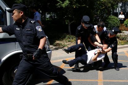 La policía detiene a un hombre en una protesta contra la decisión de las autoridades locales de asignar a sus hijos a una escuela no deseada por los padres en Pekín, China.