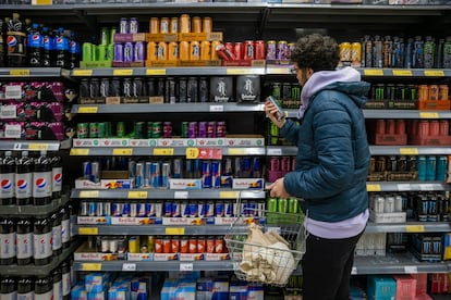 Un joven mira la sección de bebidas energéticas en el supermercado.