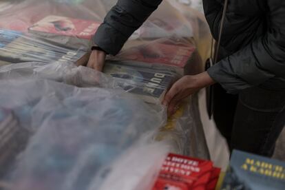 Una persona cubre los libros con plásticos para evitar que se mojen a causa de la lluvia, este martes en Barcelona.

