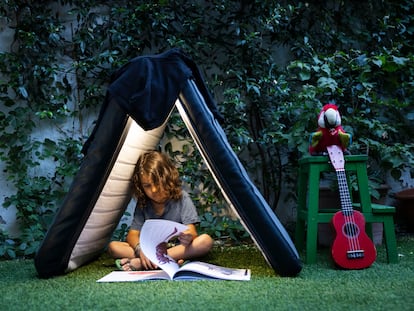 Un niño lee un libro en el patio de su casa.