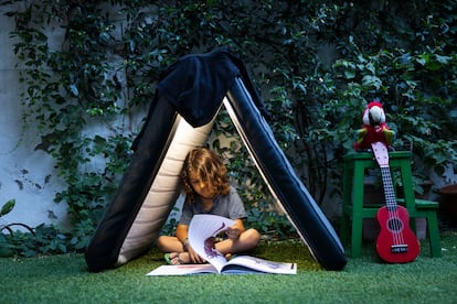 Un niño lee un libro en el patio de su casa.