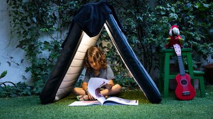 Un niño lee un libro en el patio de su casa.