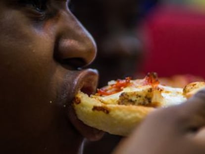 Un hombre come pizza en un restaurante.