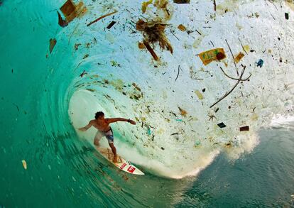 "Agua y aire, los dos elementos esenciales de los que depende toda vida, se han convertido en dos contenedores globales de basura", Jacques-Yves Cousteau. La fotografía, tomada en Java (Indonesia), la isla más poblada del mundo, muestra al surfista indonesio Dede Surinaya tomando una ola que arrastra una gran cantidad de basura. El libro 'Overdevelopment, Overpopulation, Overshoot' recoge instantáneas como esta para mostrar las "tragedias sociales y ecológicas" que generan el crecimiento de la población mundial y el consumo. Las imágenes aparecen acompañadas de citas de científicos, escritores o ecologistas, que aquí se reproducen, pues según explican sus autores, la imagen y el texto crean una "sinergia" que ayuda a comprender ese impacto en el medio ambiente que la publicación pretende denunciar.