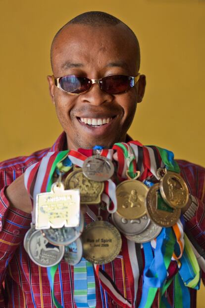 Henry Wanyoike, sosteniendo algunas de las medallas que ha ganado en atletismo.