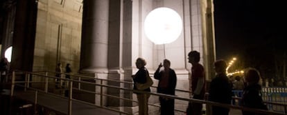 Participantes de la Noche en Blanco cruzan la Puerta de Alcalá por la pasarela de Eugenio Ampudia.
