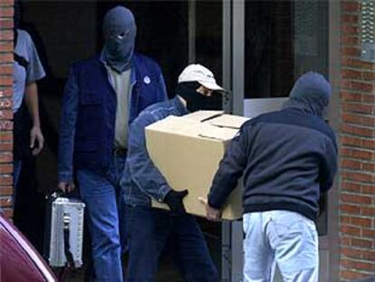 Agentes de la Ertzaintza se llevan documentación y material informático tras el registro de dos pisos en Bilbao.