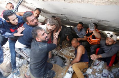 Palestinos rescatan a una niña entre los escombros de un edificio en Gaza, este domingo.