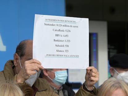 Un hombre sostiene un cartel con datos de los beneficios de la banca en una protesta contra la exclusión financiera, este lunes en A Coruña.