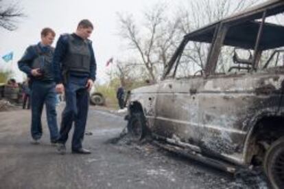 La policía ucraniana investiga un coche incendicado en frente de un puesto de control prorruso en las afueras de la ciudad insurgente de Slaviansk, en la región oriental de Donetsk, epicentro de la sublevación contra Kiev.