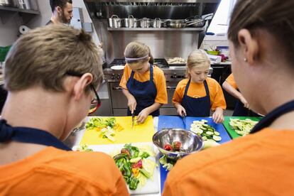 Alumnos cortando verdura en clase de cocina.