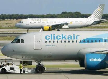 Un avión de Clickair y otro de Vueling coinciden en las pistas en el aeropuerto de El Prat, en Barcelona.