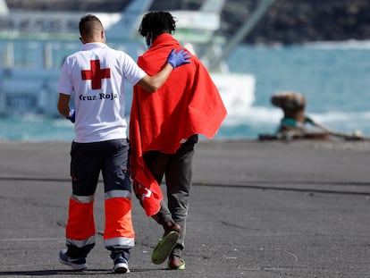 Un voluntario de la Cruz Roja acompaña a un inmigrante en el puerto de Arguineguin