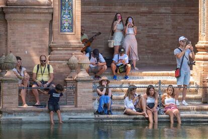 Varias personas se refrescaban el viernes, cobijadas del sol, en el estanque de la plaza de España de Sevilla.
