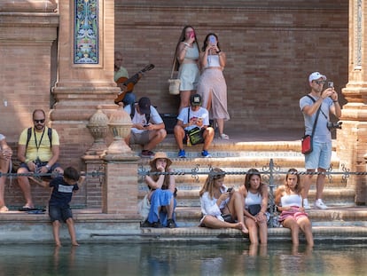 Varias personas se refrescaban el viernes, cobijadas del sol, en el estanque de la plaza de España de Sevilla.