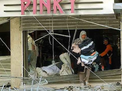 Dos mujeres se llevan ropa de una tienda de Beirut afectada por los bombardeos israelíes.