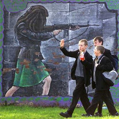 Unos adolescentes caminan al lado de un muro de ladrillos en Belfast.