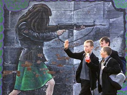 Unos adolescentes caminan al lado de un muro de ladrillos en Belfast.