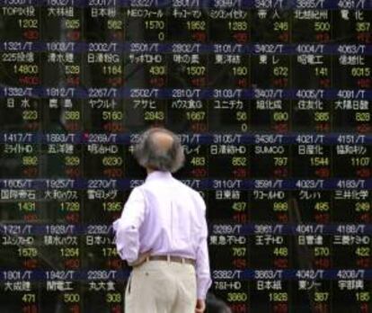 Un hombre observa información bursátil en una pantalla en la Bolsa de Tokio.