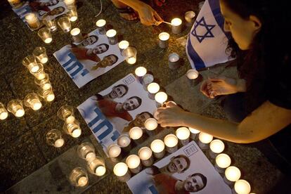 Una mujer enciende velas en Tel Aviv, junto a la foto de los tres jóvenes cuyos cadáveres fueron hallados cerca de Hebrón. El primer ministro Netanyahu ha acusado a Hamás del secuestro y asesinato de los chavales.