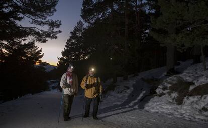 Unos excursionistas realizan una ruta a punto de anochecer en Peñalara, desde el camino que sale desde el puerto de Cotos.