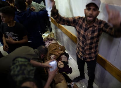 Un hombre pide ayuda para atender a dos heridos que permanecen en el suelo del hospital Nasser en Jan Yunis, tras un ataque israelí este domingo. 