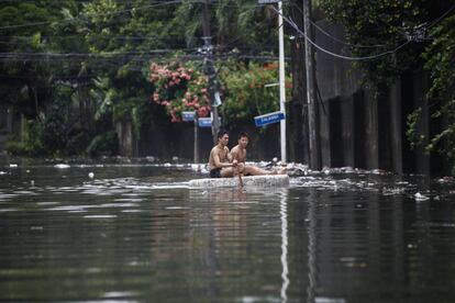 Dos personas reman sobre una balsa improvisada a travs de una calle inundada en Quezon City, al este de Manila (Filipinas).