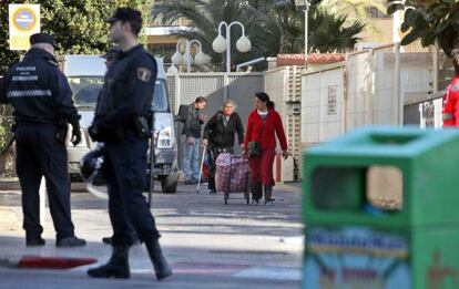 Varios de los desalojados abandonan el edificio con sus pertenencias en presencia de la policía.