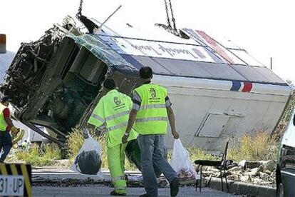 Varios operarios retiran pertenencias de los turistas suecos que viajaban en el autobús tras el accidente.