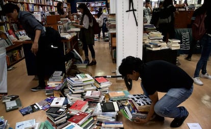 Estudiantes recogen libros tras los destrozos.