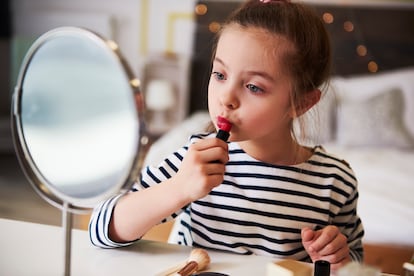 Una niña, maquillándose los labios.