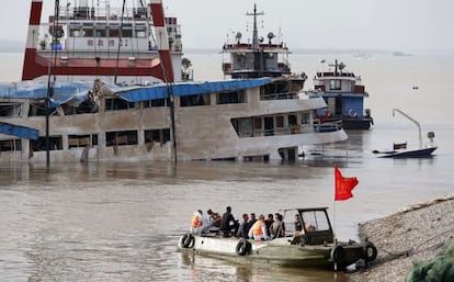 Trabalhadores sobre o barco que naufragou, depois de endireitá-lo.