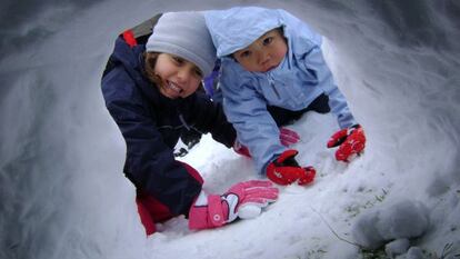 Dos niños construyendo un iglú de nieve en una de las actividades de Solomonte Experiencias, en en Pirineo de Huesca.