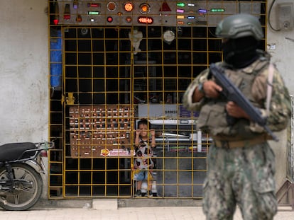 A child looks through a grille at a soldier stationed on the street in Guayaquil, Ecuador.
