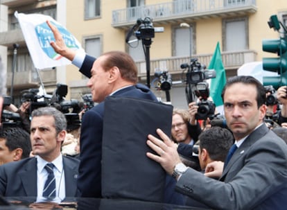 Un grupo de guardaespaldas cubre al primer ministro italiano, Silvio Berlusconi, a su salida del Palacio de Justicia de Milán.