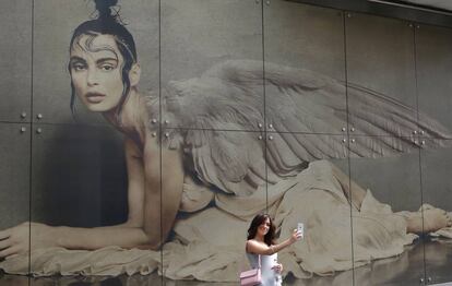 Una mujer se fotografía frente a un anuncio de publicidad en el centro de Milán, Italia.