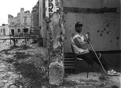 Un ciudadano bosnio mutilado posa en abril de 1995 junto a las ruinas que provocó la guerra.