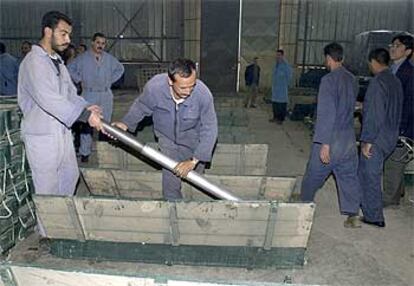 Dos trabajadores de una fábrica inspeccionada ayer por los equipos de la ONU en Irak almacenan un proyectil en una caja.