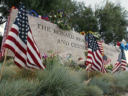 Flores y banderas,  ante el letrero de entrada a la biblioteca Ronald Reagan en Simi Valley (California).