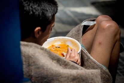 Un hombre come la sopa que le entregaron en la fila.