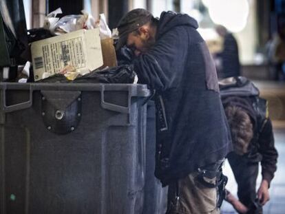 Personas buscan comida en la basura en Barcelona.