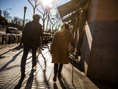 Una mujer mayor camina con un bastón por la calle de Alcalá, en Madrid