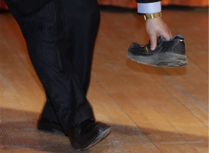 Un guardia de seguridad recoge el zapato lanzado al primer ministro chino, Wen Jiabao, mientras pronunciaba una conferencia en la Universidad de Cambridge (Reino Unido).