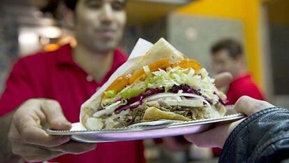 Un empleado sirve un 'kebab' en un puesto de comida rápida.