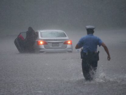 Un policía de Filadelfia acude a ayudar a una persona atascada en su coche en medio de una inundiaciíon producto del huracán Isaias.